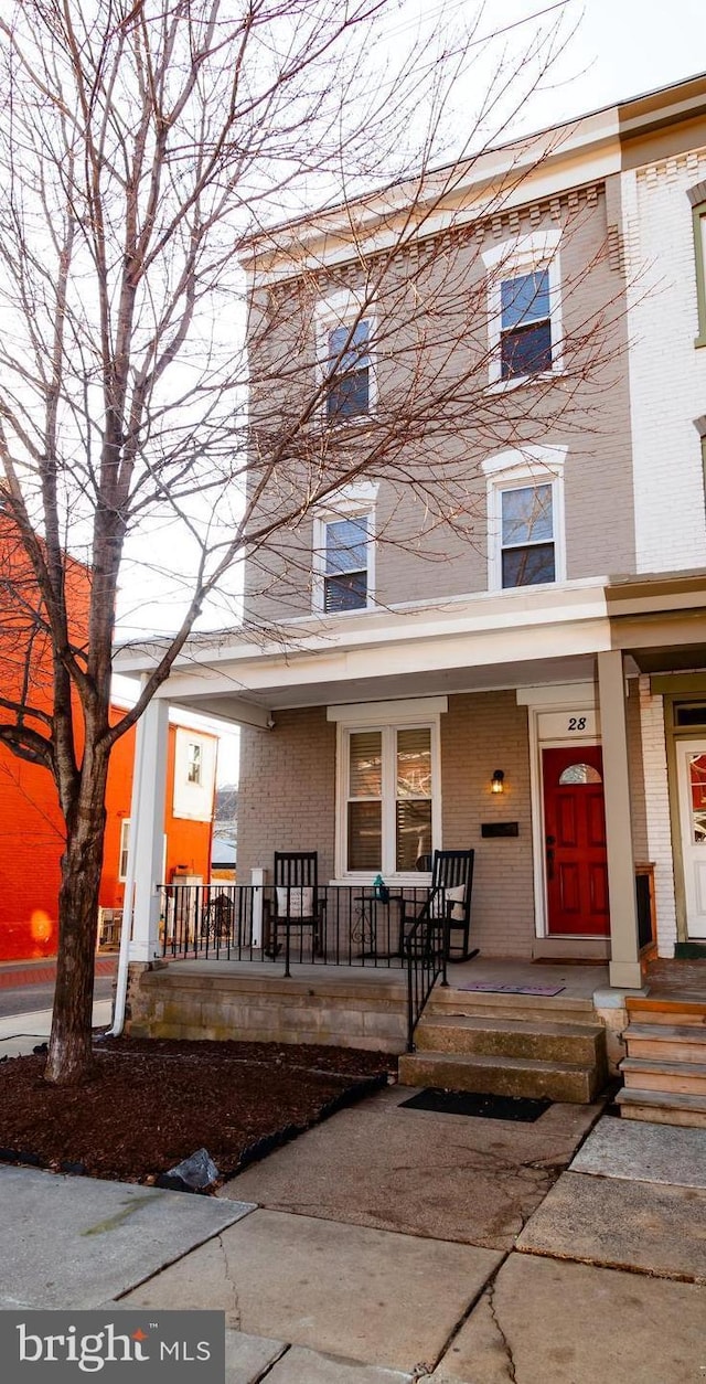 multi unit property featuring a porch and brick siding