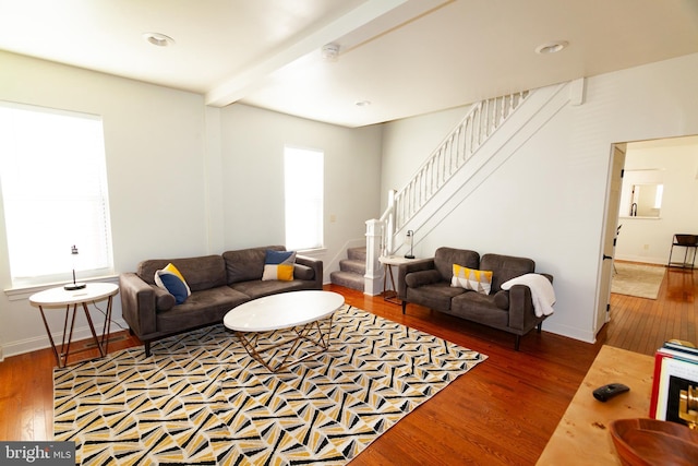 living area with stairs, beamed ceiling, a wealth of natural light, and wood finished floors