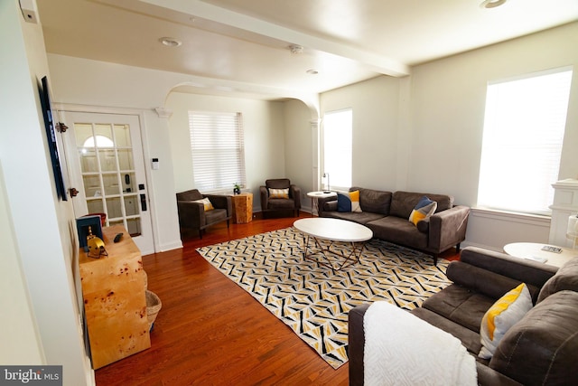 living room featuring arched walkways, wood finished floors, and beamed ceiling