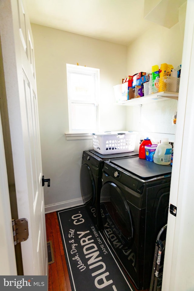 washroom featuring visible vents, wood finished floors, washer and dryer, laundry area, and baseboards