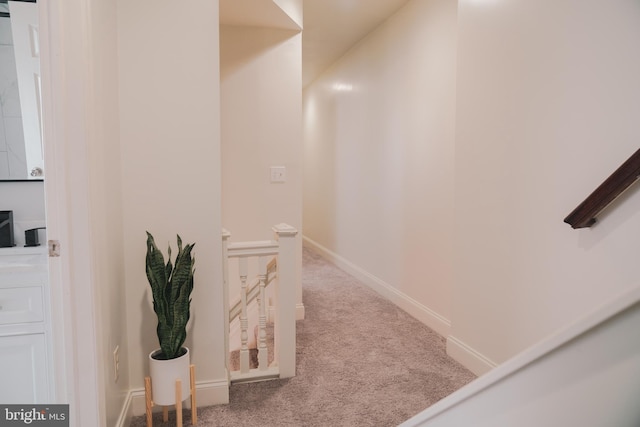 hallway featuring carpet floors, an upstairs landing, and baseboards