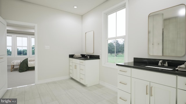 ensuite bathroom with two vanities, a sink, baseboards, and ensuite bath