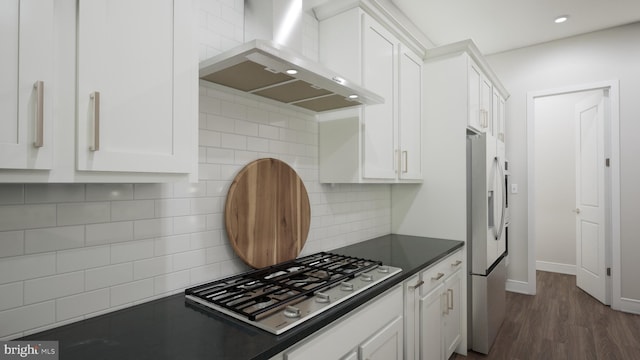 kitchen with stainless steel appliances, dark countertops, white cabinetry, and wall chimney exhaust hood