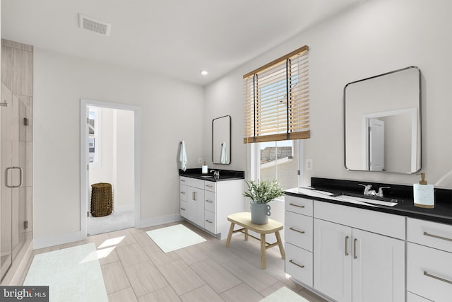 bathroom with a sink, visible vents, two vanities, and a shower stall