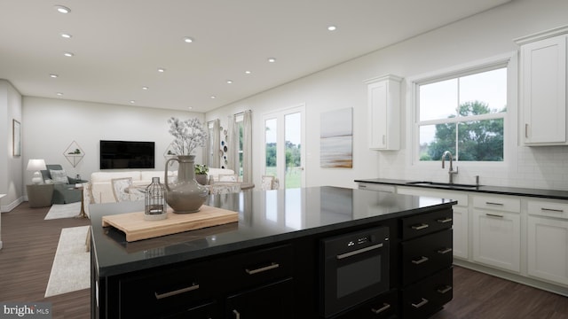 kitchen featuring dark wood finished floors, wall oven, a sink, and dark countertops