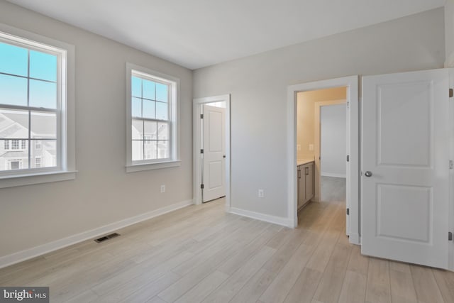 unfurnished bedroom featuring light wood-type flooring, baseboards, and visible vents