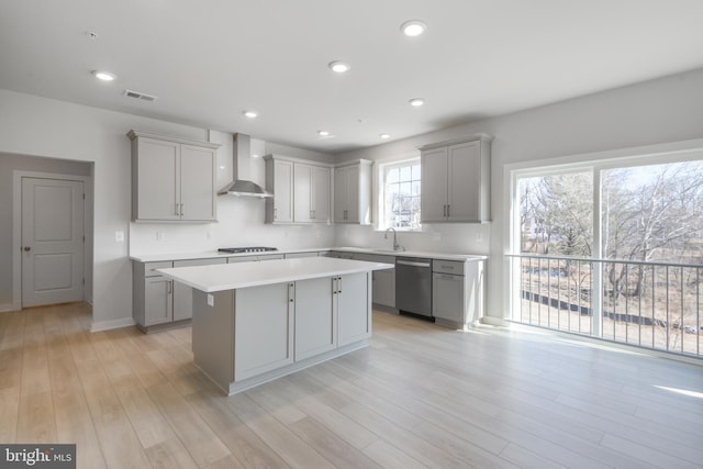 kitchen featuring a center island, gray cabinets, visible vents, dishwasher, and wall chimney exhaust hood