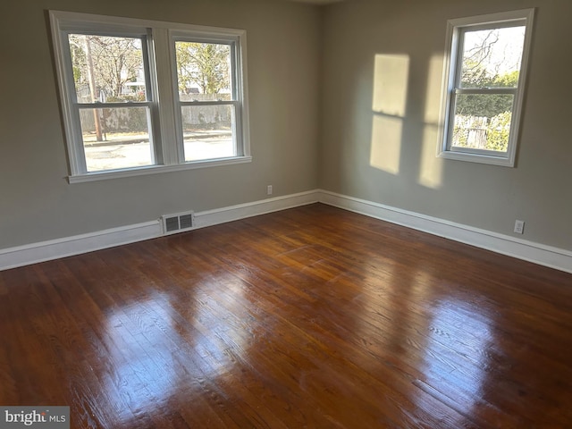 unfurnished room featuring baseboards, visible vents, and dark wood-style flooring