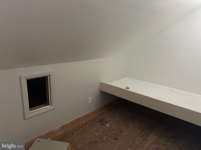 unfurnished bedroom with dark wood-style floors and lofted ceiling