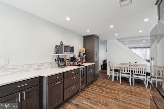 kitchen featuring tasteful backsplash, visible vents, dark wood finished floors, stainless steel microwave, and light countertops