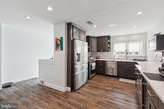 kitchen featuring tasteful backsplash, visible vents, stainless steel appliances, and dark wood-type flooring