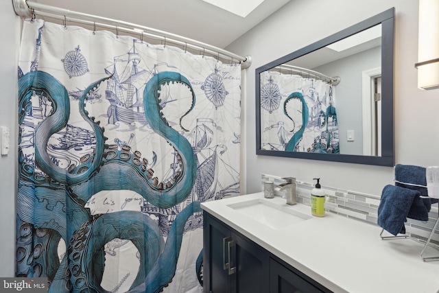 full bath featuring a skylight, backsplash, and vanity