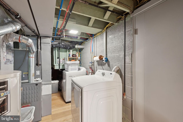 clothes washing area featuring laundry area, washer and clothes dryer, and wood finished floors