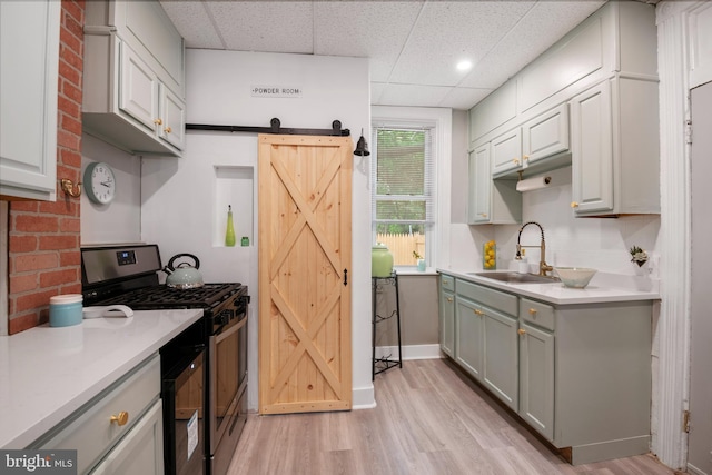 kitchen featuring light countertops, stainless steel gas stove, a sink, and a barn door