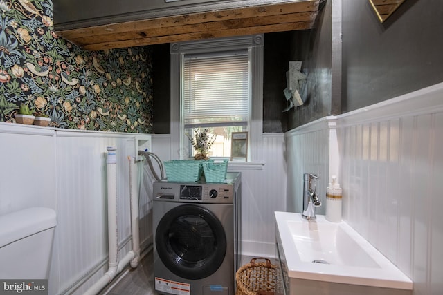 washroom featuring laundry area, washer / clothes dryer, wainscoting, and a sink