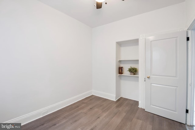 empty room featuring ceiling fan, baseboards, and wood finished floors