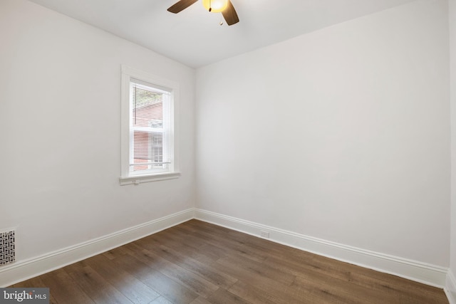 spare room featuring a ceiling fan, dark wood-style flooring, visible vents, and baseboards