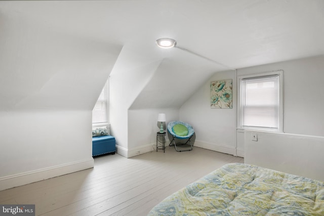 bedroom with vaulted ceiling, hardwood / wood-style flooring, and baseboards