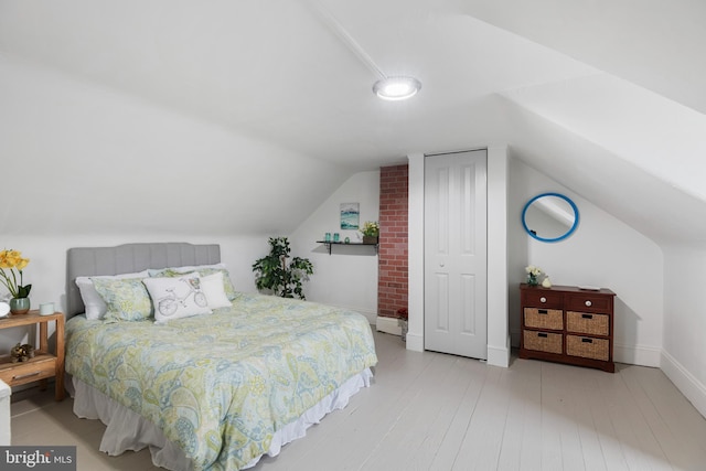 bedroom with lofted ceiling, wood finished floors, and baseboards