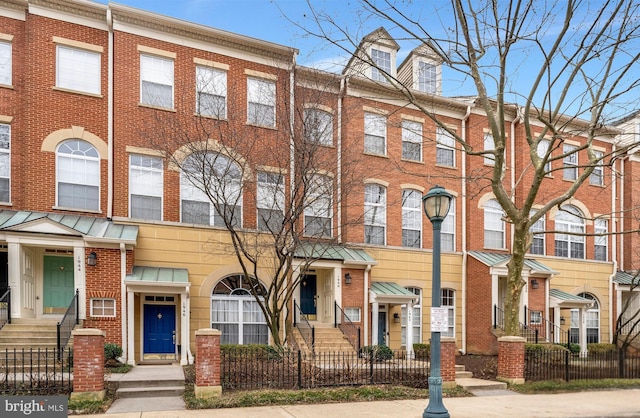 townhome / multi-family property with a fenced front yard and brick siding