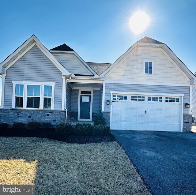 view of front of house with driveway, stone siding, and an attached garage