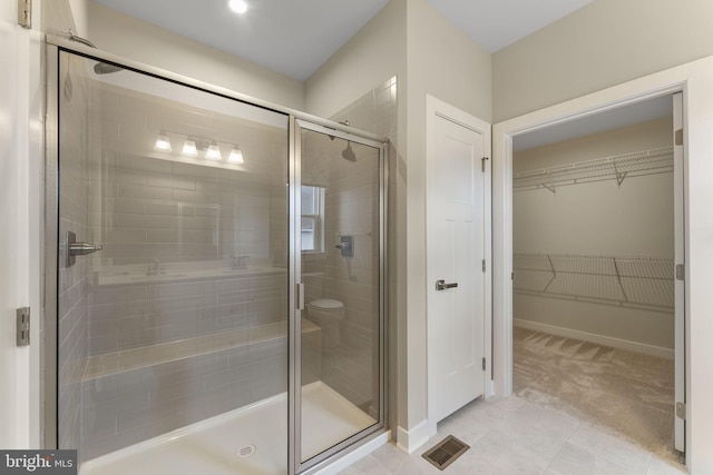 full bathroom featuring a stall shower, baseboards, visible vents, tile patterned floors, and a spacious closet