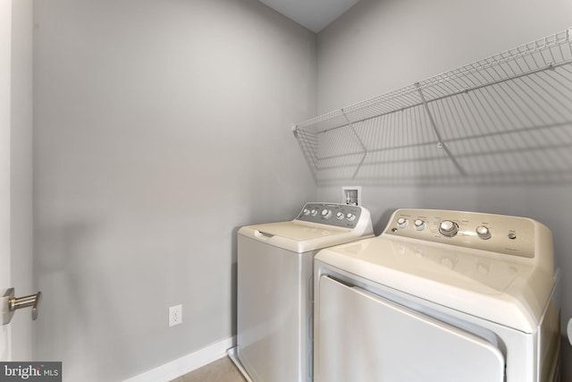 clothes washing area with laundry area, baseboards, and washer and dryer