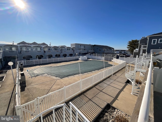 community pool with a residential view, fence, and a patio