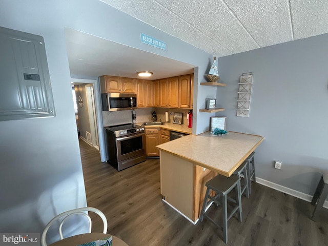 kitchen featuring light countertops, appliances with stainless steel finishes, electric panel, a peninsula, and a kitchen breakfast bar