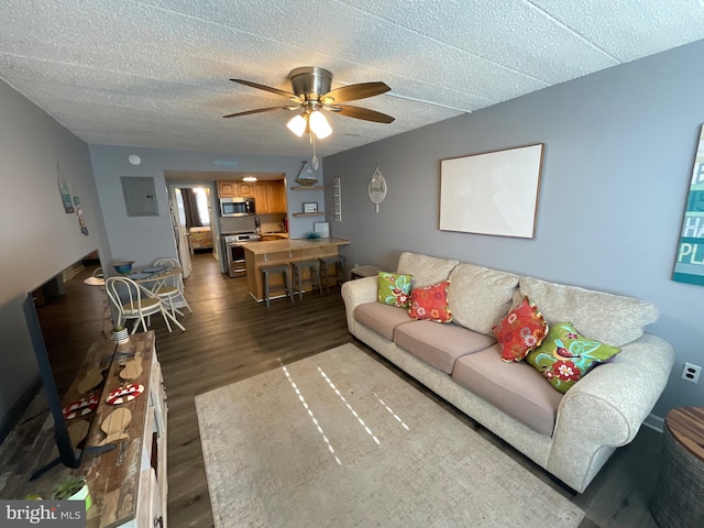 living room with ceiling fan, a textured ceiling, and dark wood-style flooring