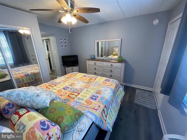 bedroom featuring ceiling fan, a textured ceiling, dark wood-type flooring, baseboards, and a closet