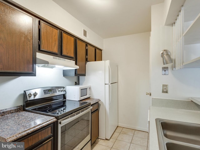 kitchen featuring light tile patterned floors, dark countertops, a sink, white appliances, and under cabinet range hood