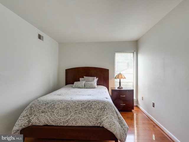 bedroom featuring visible vents, baseboards, and wood finished floors