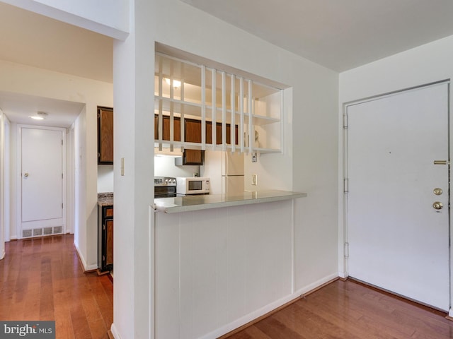 kitchen with white appliances, visible vents, wood finished floors, light countertops, and under cabinet range hood