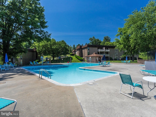 community pool with a patio area and fence