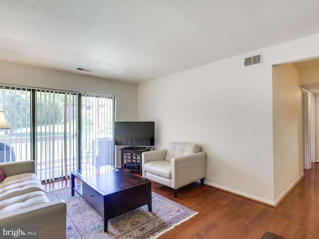 living room featuring baseboards, visible vents, and wood finished floors