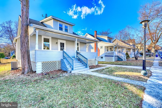 bungalow-style home with a porch, a front lawn, central AC unit, and stairway