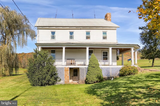 rear view of property featuring a porch, a yard, and a chimney