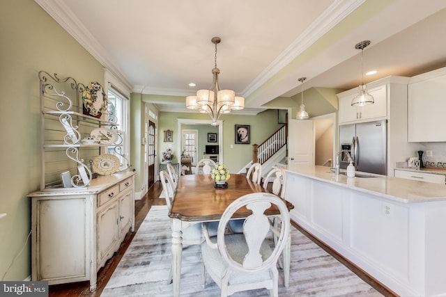 dining space featuring ornamental molding, wood finished floors, recessed lighting, a chandelier, and stairs