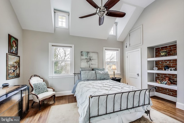 bedroom featuring ceiling fan, high vaulted ceiling, baseboards, and wood finished floors