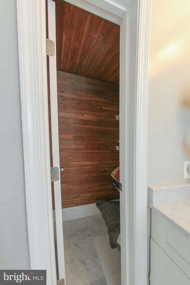 bathroom with vanity, wood ceiling, and wood walls