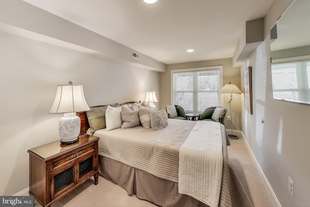 bedroom with multiple windows, visible vents, baseboards, and light carpet