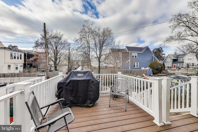 wooden terrace with grilling area, a residential view, and fence