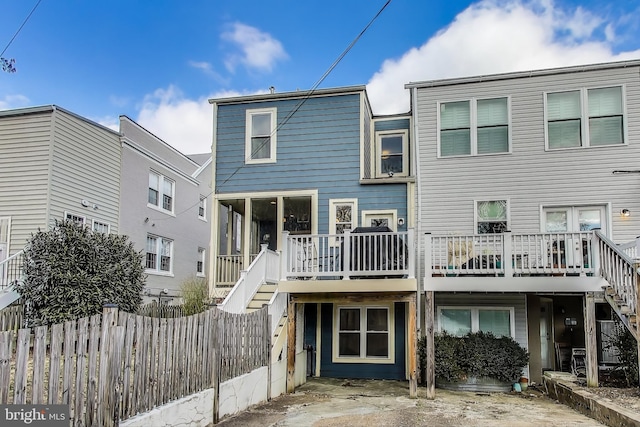 rear view of house with stairs, a deck, and fence