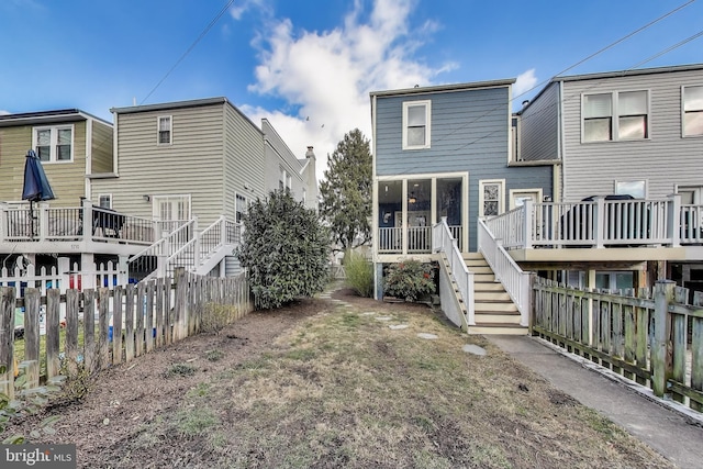 back of property with stairs, a deck, and a fenced backyard