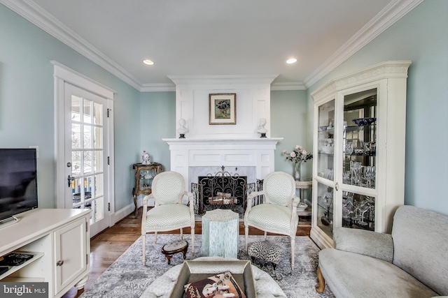 living area featuring wood finished floors, crown molding, a fireplace, and french doors