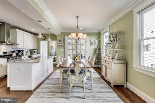 dining room featuring dark wood finished floors, an inviting chandelier, crown molding, and baseboards