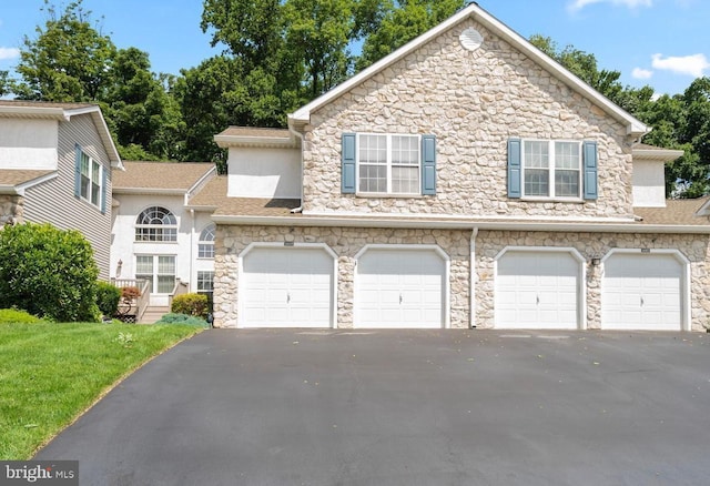 townhome / multi-family property with driveway, roof with shingles, an attached garage, and stucco siding