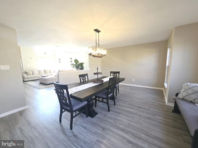 dining space featuring a notable chandelier, baseboards, and wood finished floors