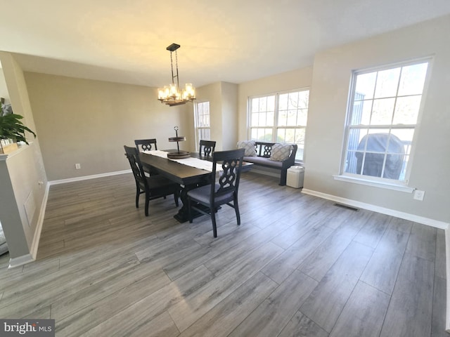 dining room featuring a notable chandelier, wood finished floors, visible vents, and baseboards